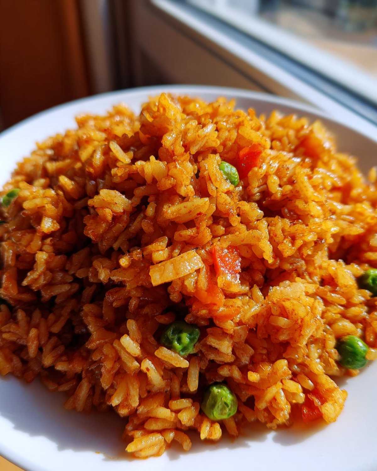 Close-up of fluffy, seasoned Spanish Rice mixed with bright green peas and diced red tomatoes.