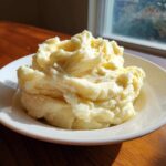 A generous serving of fluffy, creamy Steakhouse Potatoes piled high in a white bowl.