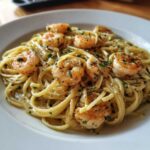 Close-up of a white plate filled with Garlic Butter Shrimp Pasta, topped with sautéed shrimp and fresh parsley.