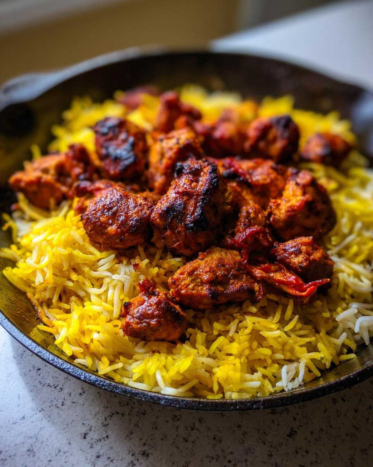 Close-up of charred, spiced One Pan Tandoori Chicken & Rice served in a dark skillet.