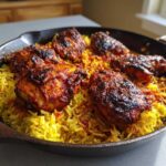 Close-up of charred, bright red One Pan Tandoori Chicken & Rice served in a dark skillet.