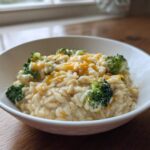 A close-up of creamy One Pot Broccoli Cheese Orzo topped with melted cheddar cheese and bright green broccoli florets.