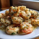 Close-up of juicy Oven Grilled Shrimp coated in garlic butter and fresh parsley served on a white plate.