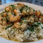 Close-up of juicy garlic shrimp served over white rice, generously topped with fresh chopped parsley.
