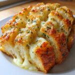 Close-up of warm, pull-apart Sliced Garlic Bread with Cheese showing melted, gooey cheese strings and herbs.