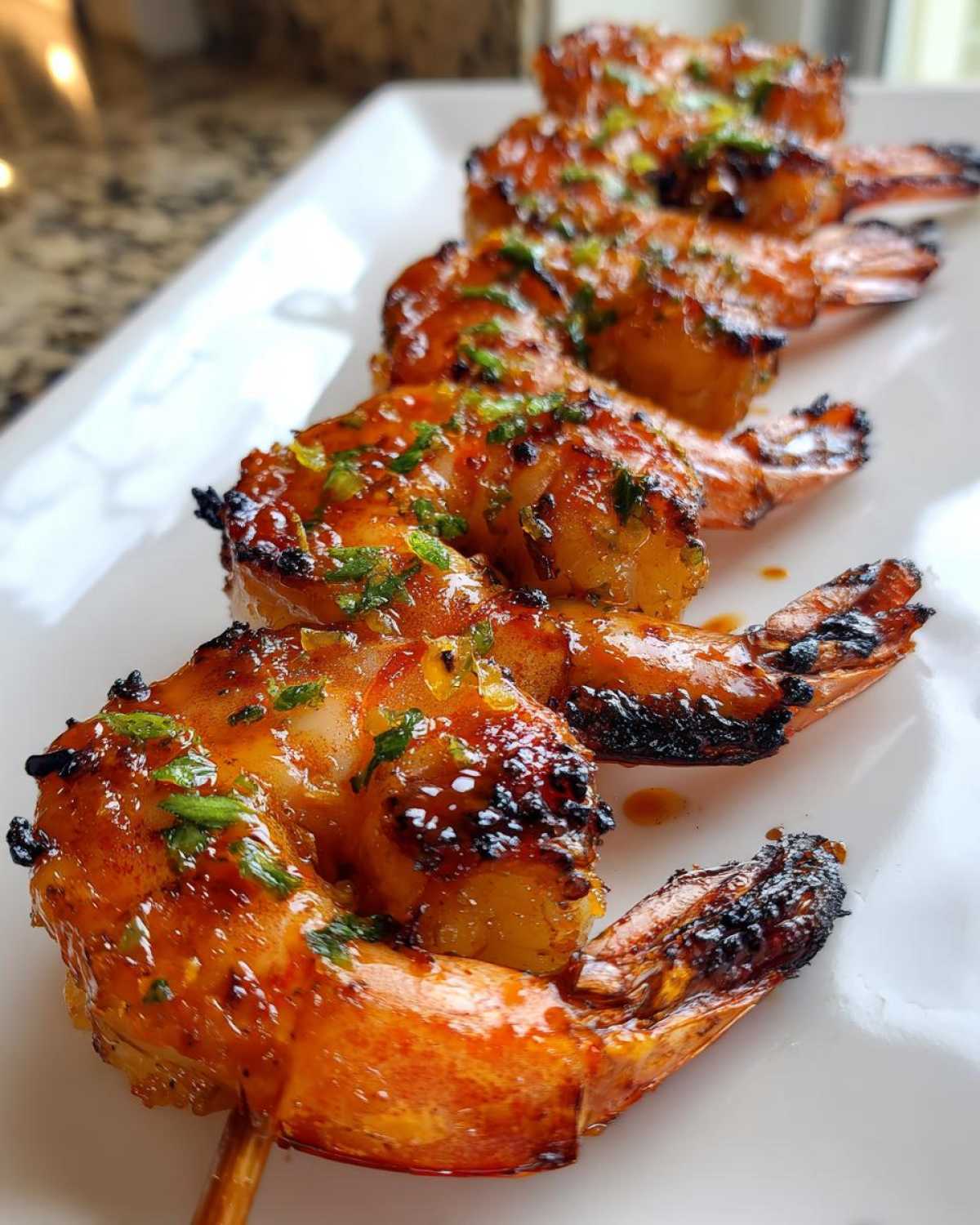 Close-up of grilled Sweet Chili Grilled Bang Bang Shrimp Skewers glazed with sauce and topped with herbs.