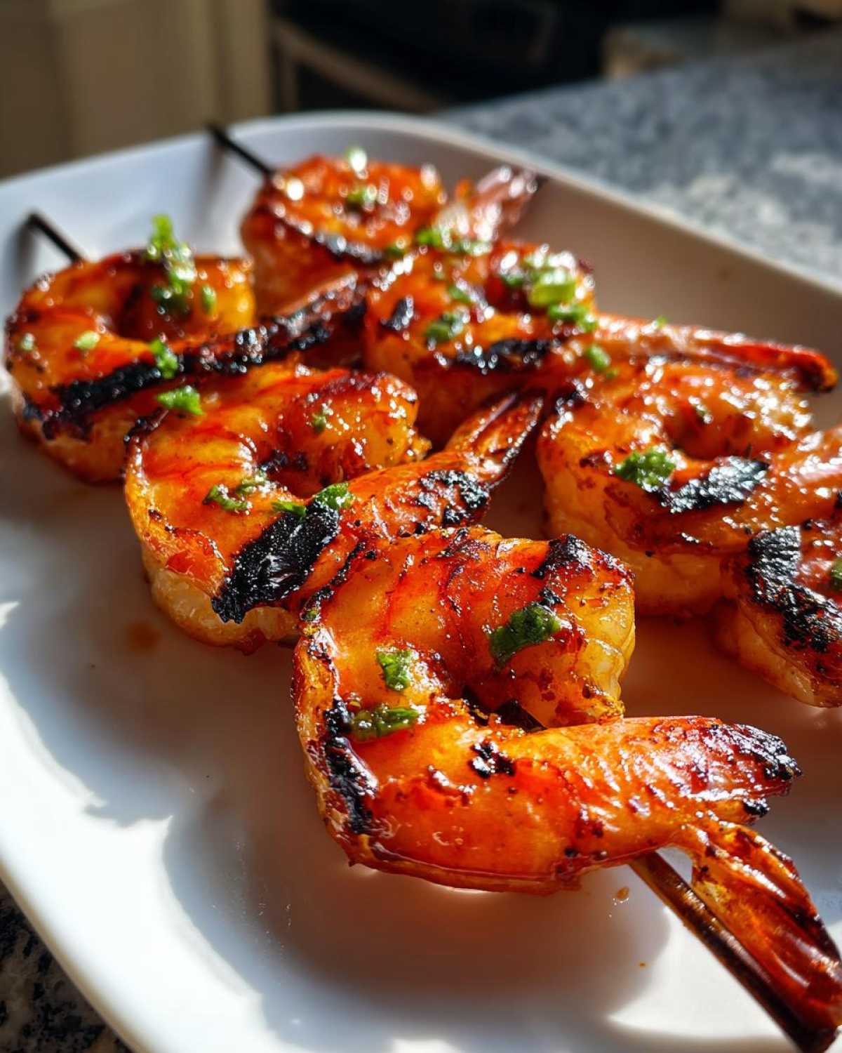 Close-up of grilled Sweet Chili Grilled Bang Bang Shrimp Skewers glazed in sauce and garnished with green herbs.
